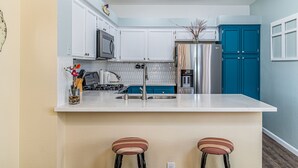 Eine moderne Küche mit weißen Schränken, einem blauen Kühlschrank und einer weißen Arbeitsplatte.