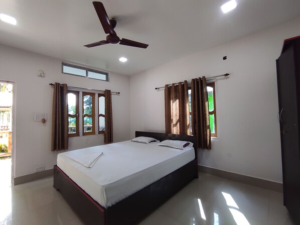 A clean, well-lit bedroom with a bed, ceiling fan, and windows with curtains.