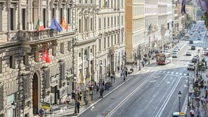 Une large rue bordée de bâtiments historiques, un panneau McDonald's et un ciel dégagé.