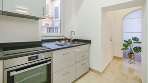 Une cuisine moderne dotée d’un four encastré, d’un évier et d’une fenêtre laissant entrer la lumière naturelle.