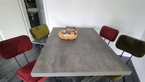 Ein Esstisch mit einem gewobenen Korb, der eine ZANA'S Karte enthält, umgeben von vier Stühlen mit Metallbeinen.