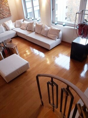 A modern living room with a sectional sofa, a small round table, and a staircase.