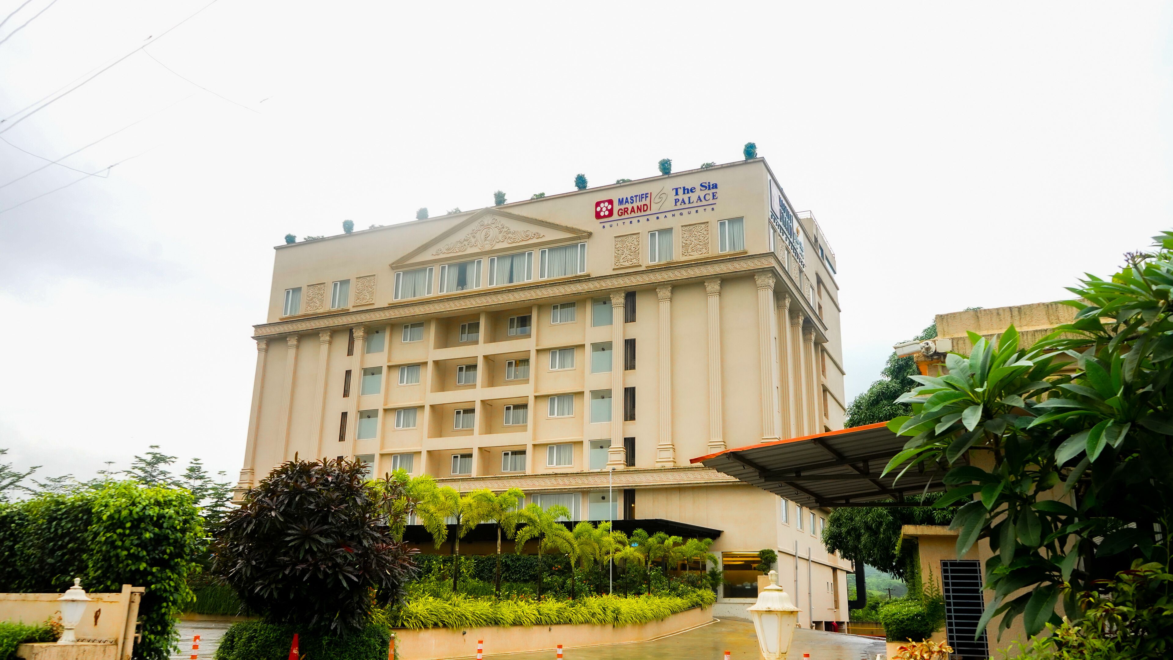 A large, multi-story hotel with a classic architectural style, featuring a prominent sign for 'Mastiff Grand Palace' and 'The Sia Palace'.
