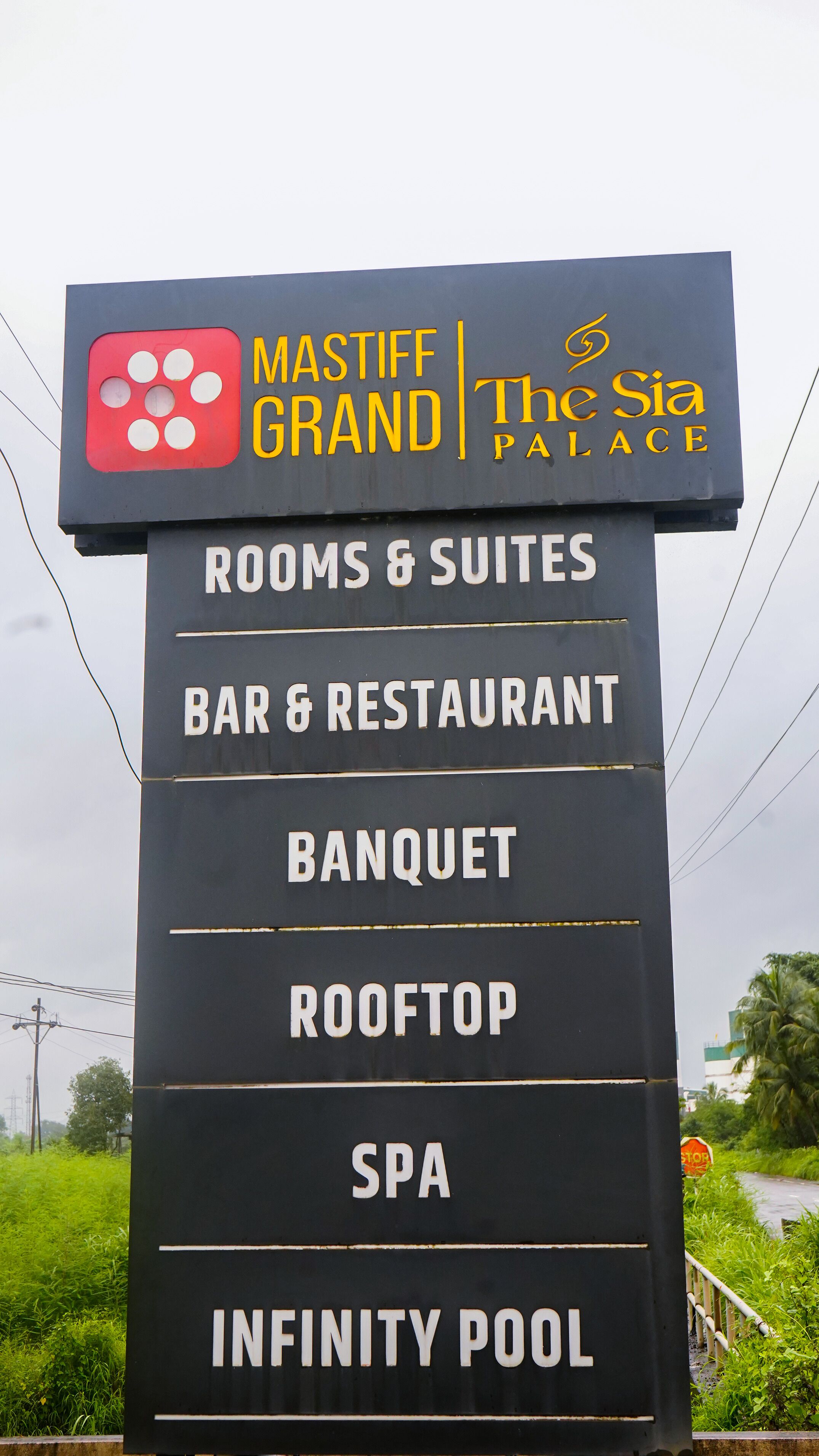 Ein Schild mit den Annehmlichkeiten des The Mia Stiff Grand, darunter Zimmer und Suiten, Bar und Restaurant, Bankettmöglichkeiten, Dachterrasse, Spa und Infinity-Pool.