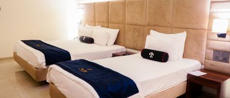 Two single beds with headboards, a bedside table, and a nightstand.