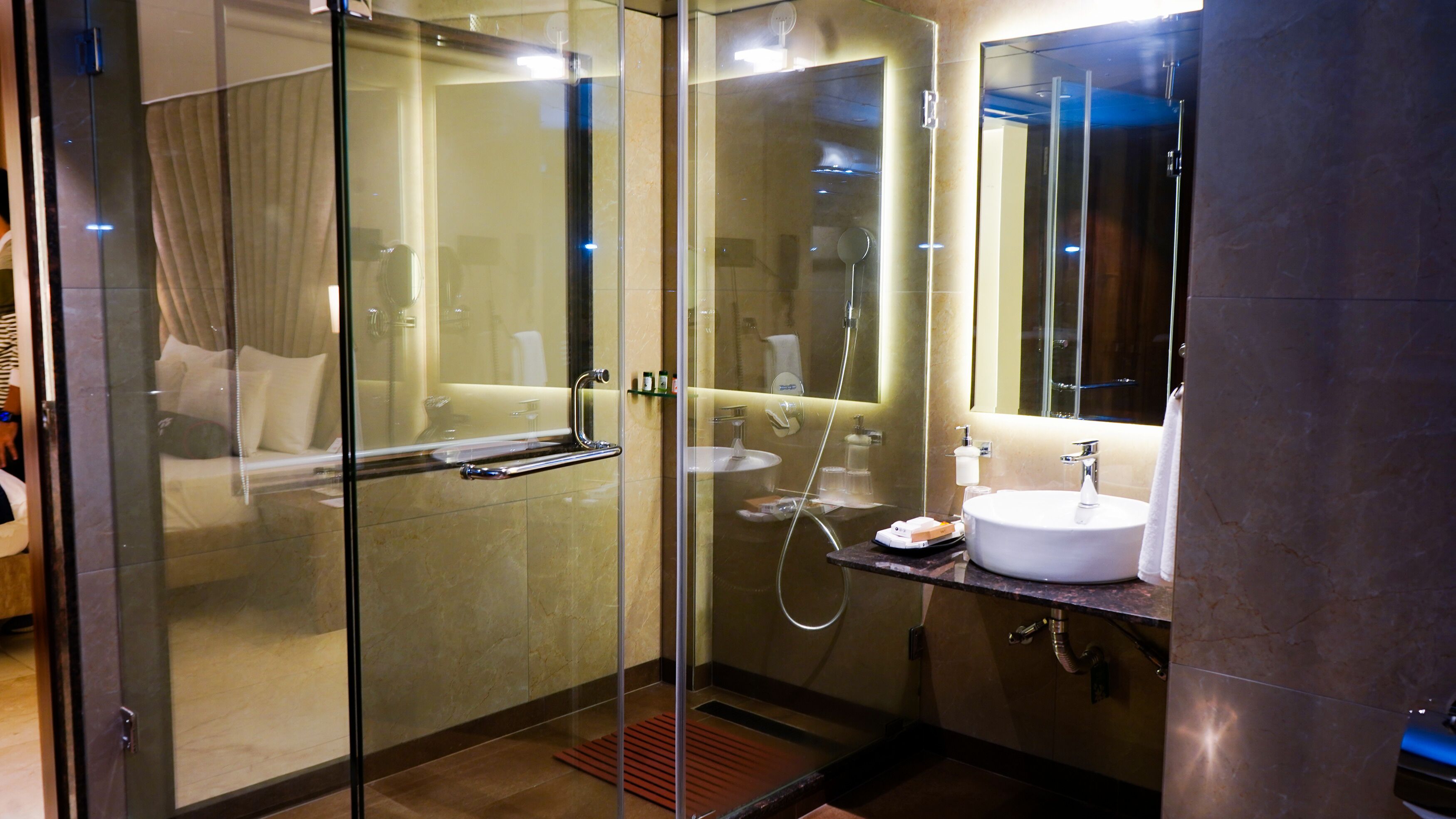 A modern bathroom with a glass-enclosed shower, a white sink, and a mirror above the sink.