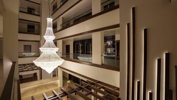 Een hotelinterieur met meerdere niveaus, een centrale kroonluchter, glazen balustrades en een modern design.