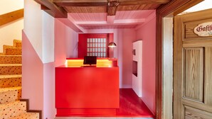 A reception desk with a red counter, a black chair, and a lamp. There is a wooden door with a sign above it. - pop-up stuub bierhäusle feldberg (Feldberg)
