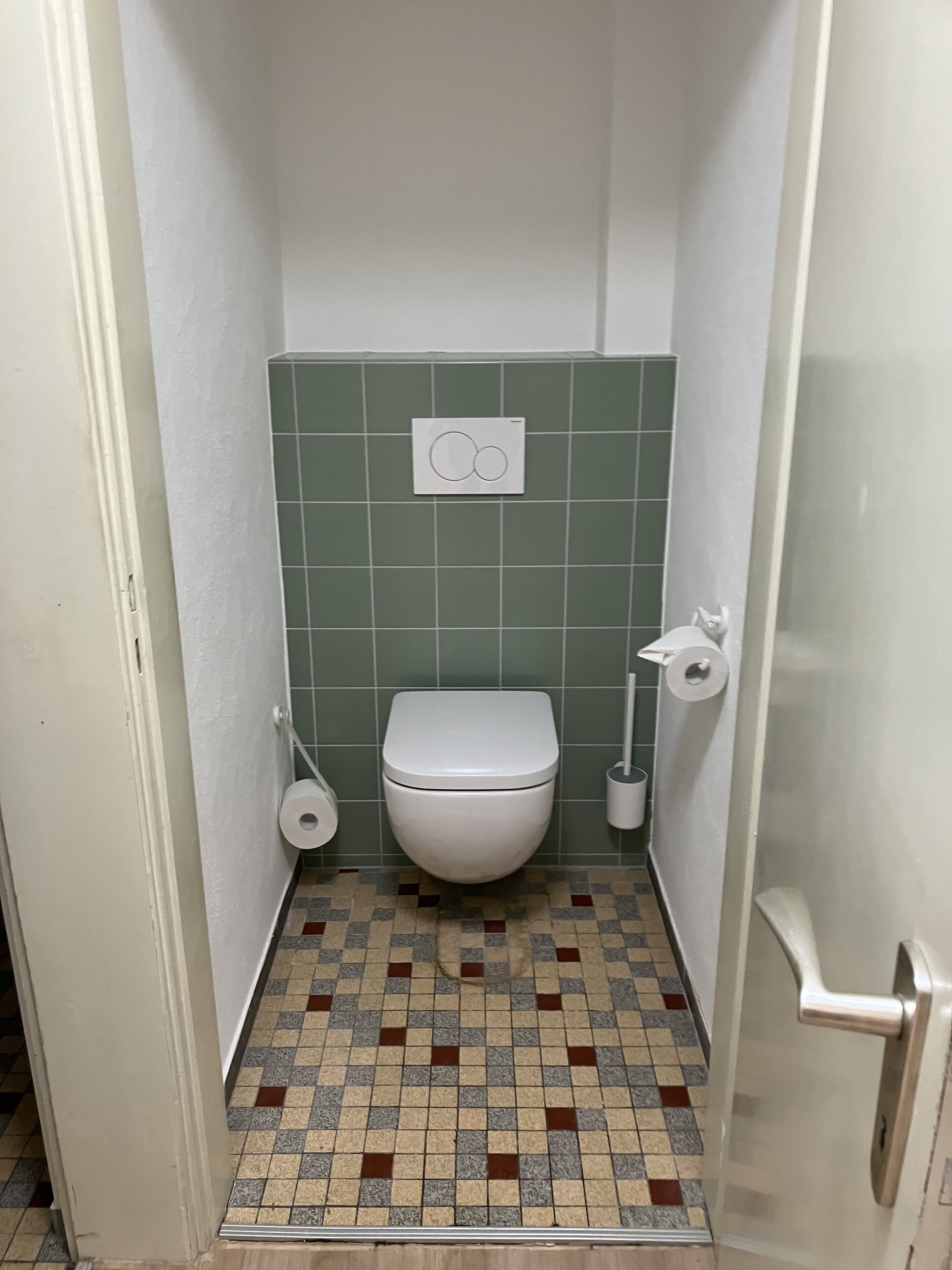 Une petite salle de bain carrelée, équipée de toilettes, d’un porte-rouleau de papier toilette et d’un bidet.
