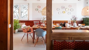 A cozy dining area with wooden furniture, a variety of plates on the wall, and a large window with a view of trees. - pop-up stuub bierhäusle feldberg (Feldberg)