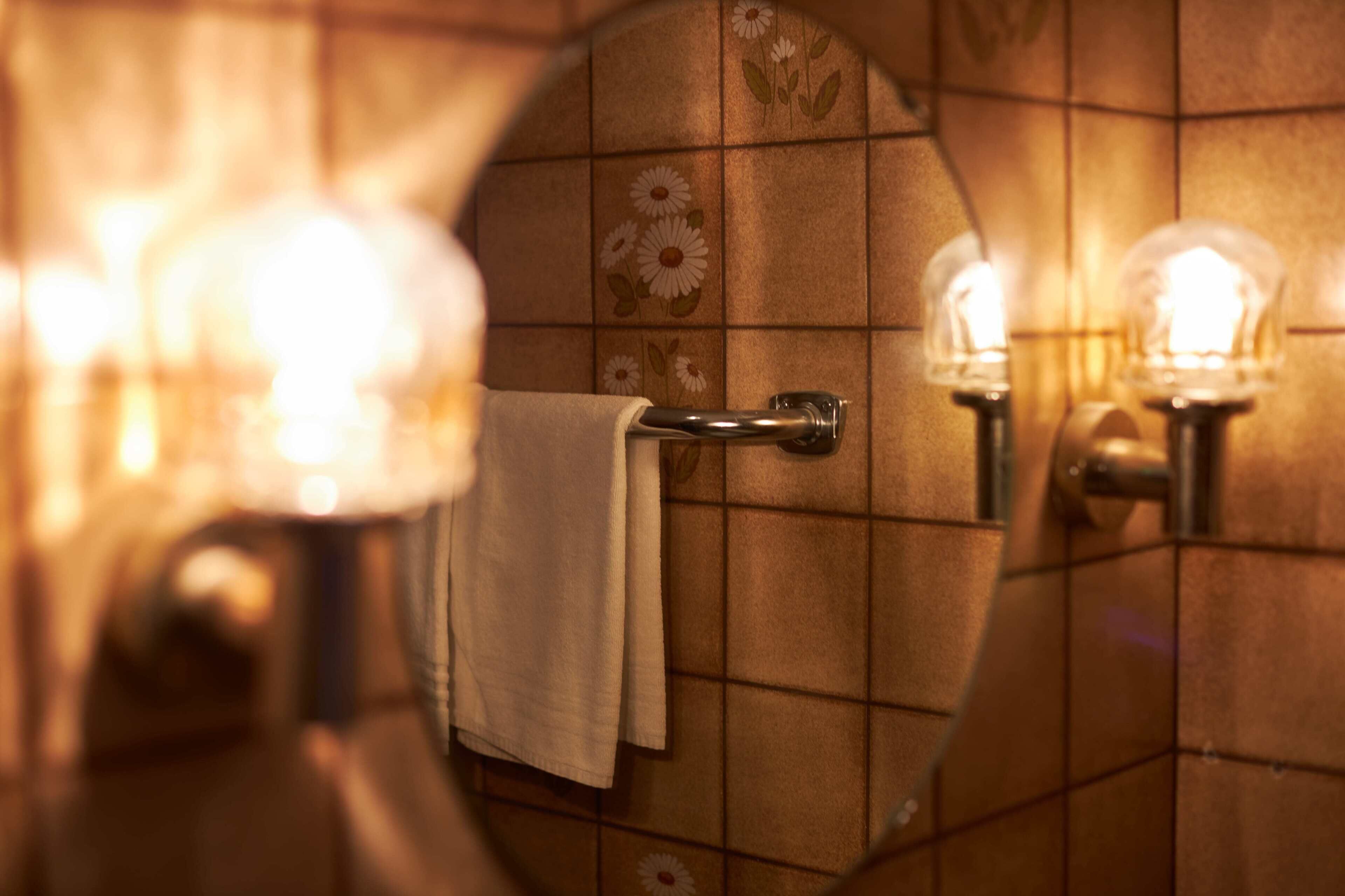 A bathroom with a towel hanging on a rack, a mirror, and two wall-mounted lights.