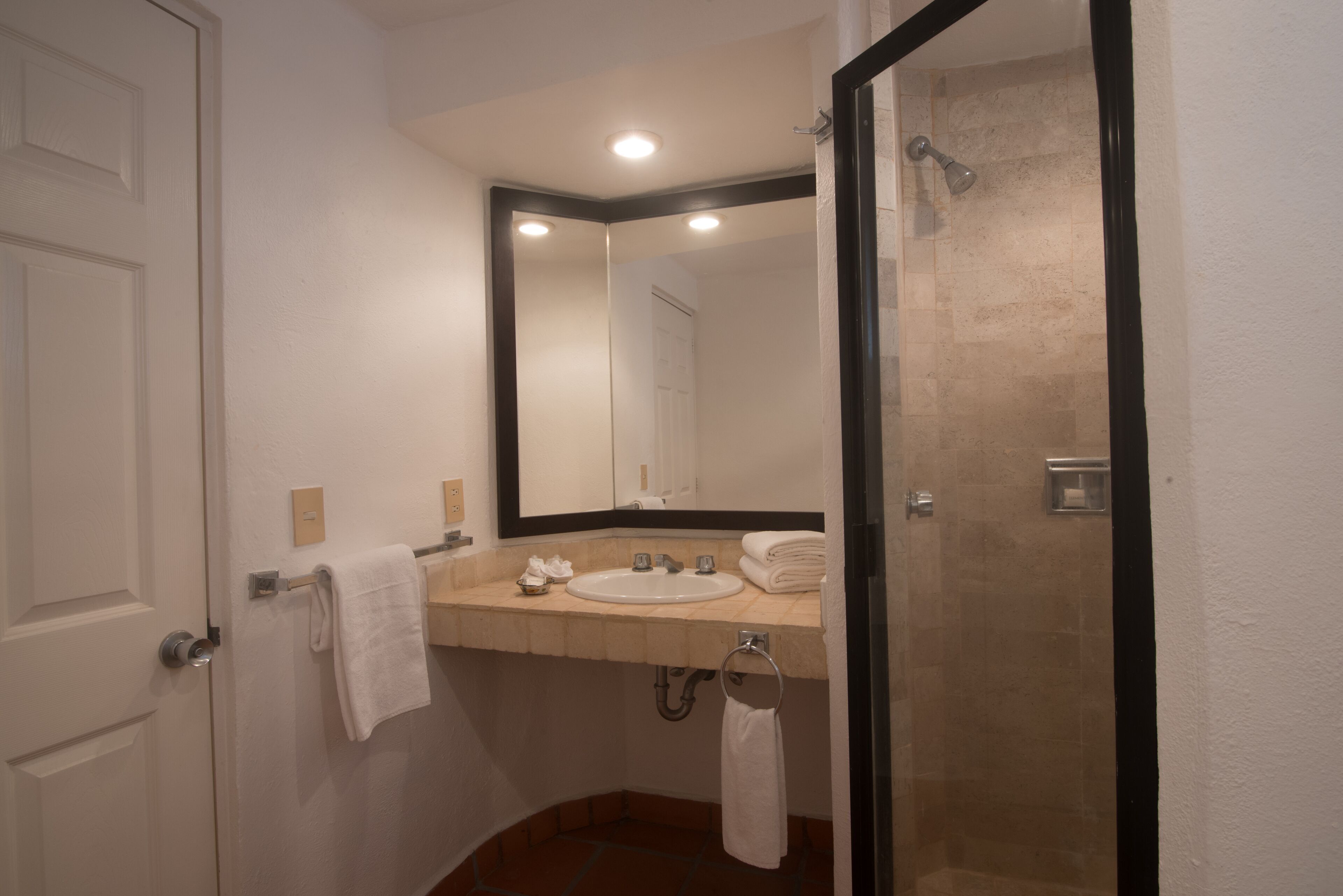 A bathroom with a sink, mirror, towel rack, and shower.
