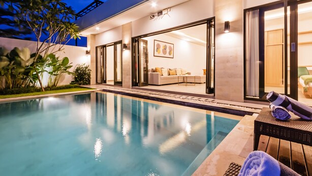 Ett modernt område vid poolen med en pool med klart vatten, en soffa och en stol.