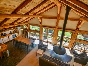A spacious loft with a high ceiling, wooden beams, a large fireplace, and a view of the outdoors. - Modern chalet for 10 near slopes with parking and WIFI (Morzine)