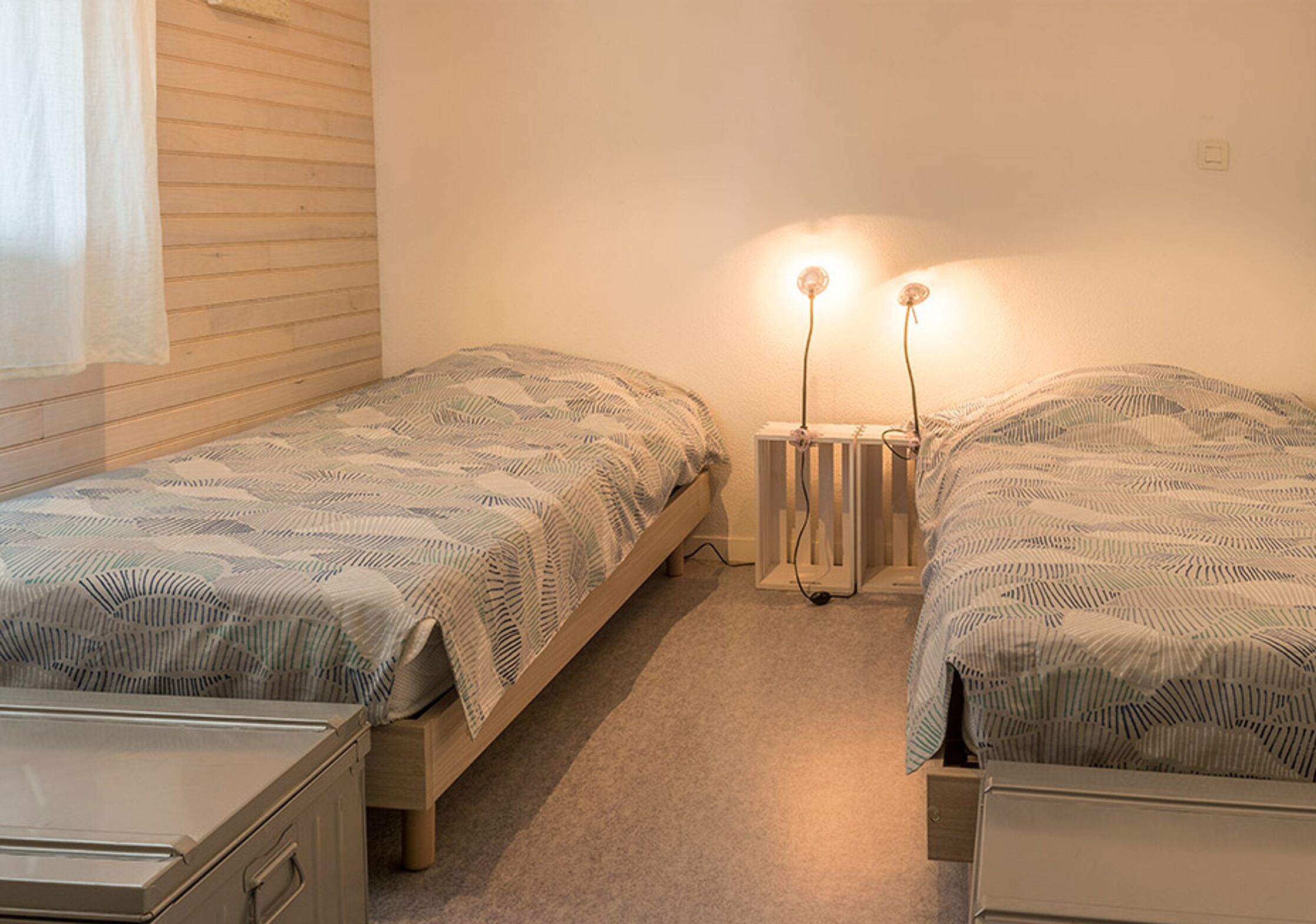 A twin room with two single beds, a radiator, and a small cabinet.