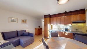 Ein modernes Wohnzimmer mit einer Couch, einem Esstisch und einer Küchenzeile mit Holzsärchen und einem Herd.