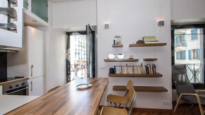 Una cocina moderna con una mesa de comedor de madera, estantes empotrados y vistas a la ciudad a través de una ventana.