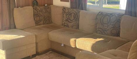 A living room with a sectional sofa, a small rug, and a window with curtains.