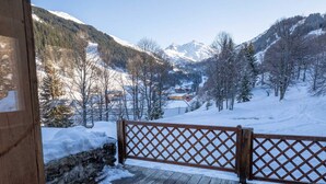 A wooden deck with a lattice railing overlooking a snowy mountain landscape. - Spacious chalet in Méribel with sunny terrace and fireplace (Méribel)
