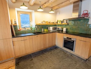 A kitchen with wooden cabinets, a microwave, a toaster, and a sink. - Spacious chalet in Méribel with sunny terrace and fireplace (Méribel)