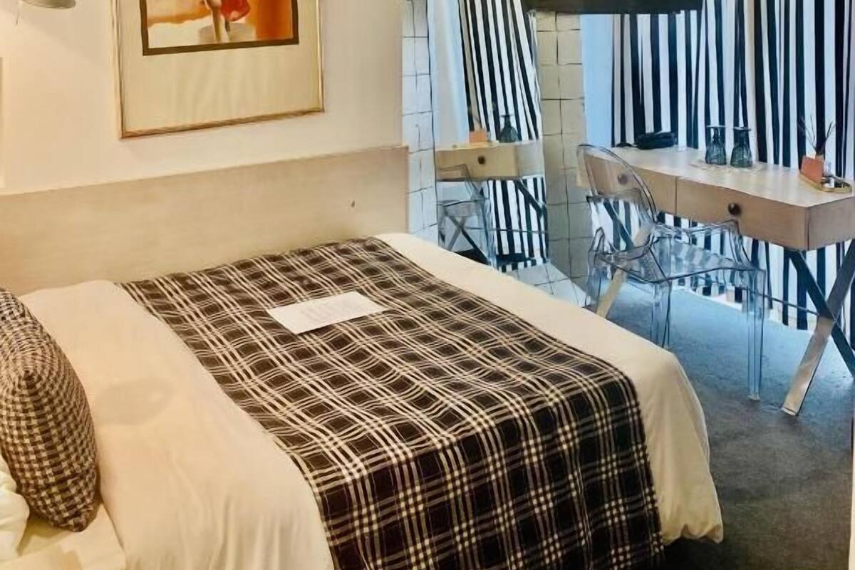 A hotel room with a bed, a desk, a chair, a television, and a framed picture on the wall.