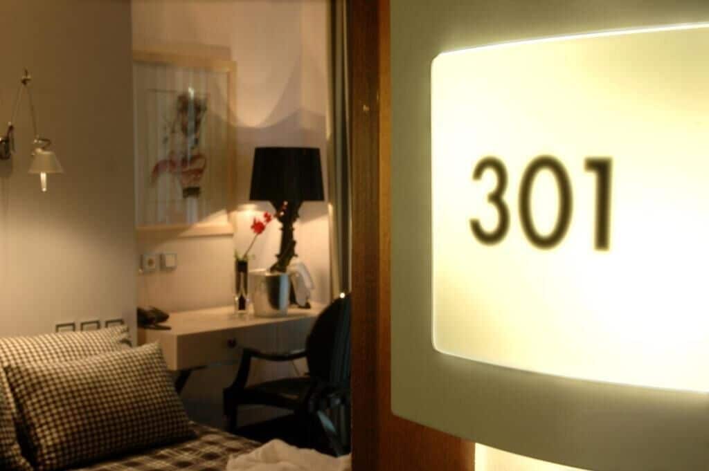 A hotel room with a bed, a desk, and a lamp. The room number is 301.