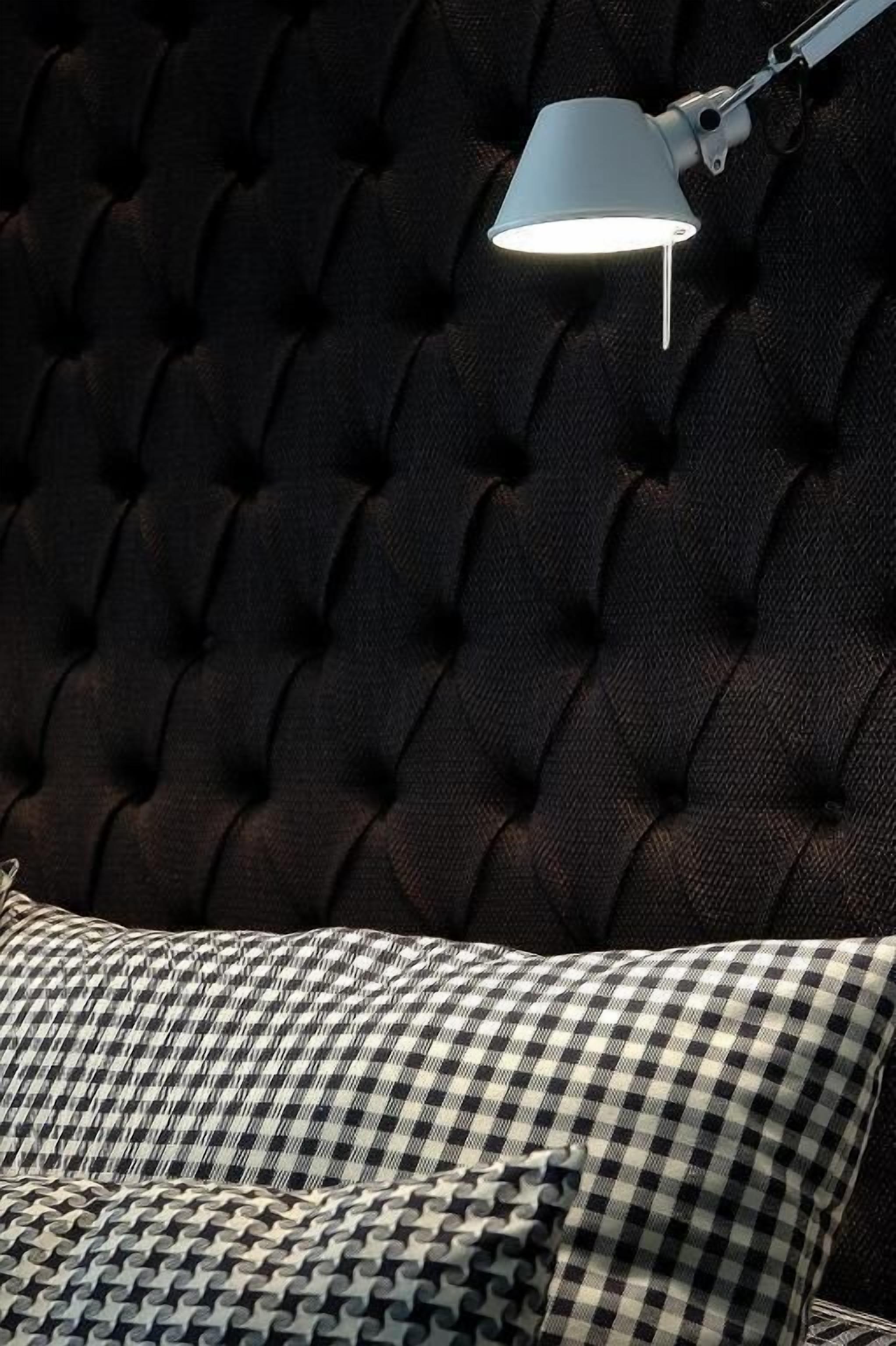 A tufted headboard with a lamp on it.