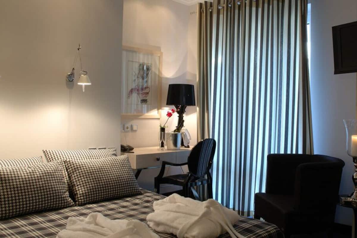 A hotel room with a bed, a desk, a chair, a TV, and a window with curtains.