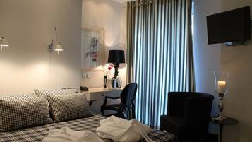 A hotel room with a bed, a desk, a chair, a TV, and a window with curtains.