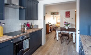 Een moderne keuken met donkere kastjes, een houten aanrecht en een eetgedeelte met een houten tafel en stoelen.