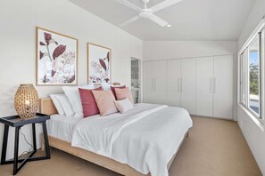 A bedroom with a bed, a bedside table, a ceiling fan, and a wardrobe.