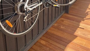 A white bicycle with a water bottle and a red seat, leaning against a wooden fence. - Stylish Yarraville retreat, moments from the village (Yarraville)