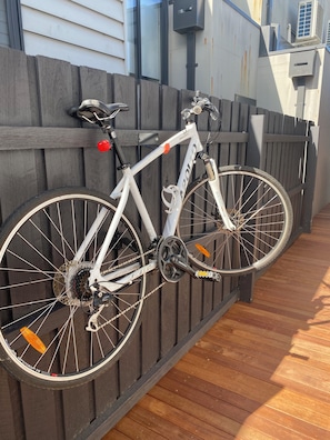A white bicycle with a water bottle and a red seat, leaning against a wooden fence. - Stylish Yarraville retreat, moments from the village (Yarraville)