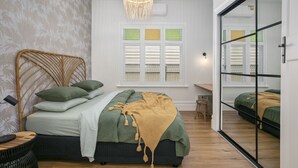 A bedroom with a bed, a bedside table, a chair, a window with shutters, and a hanging light fixture. - Stylish Yarraville retreat, moments from the village (Yarraville)