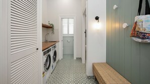 A laundry area with a washing machine, a drying rack, and a bench. - Stylish Yarraville retreat, moments from the village (Yarraville)