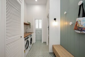 A laundry area with a washing machine, a drying rack, and a bench. - Stylish Yarraville retreat, moments from the village (Yarraville)