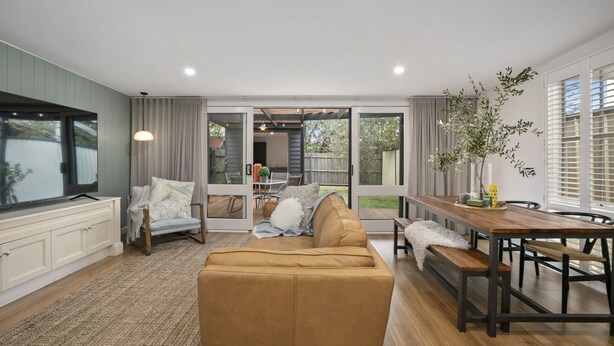 A modern living room with a sofa, a dining table, and a large window. - Stylish Yarraville retreat, moments from the village (Yarraville)