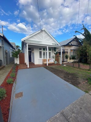 A residential house with a covered porch, a front yard with a red mulch border, and a clear blue sky. - Stylish Yarraville retreat, moments from the village (Yarraville)