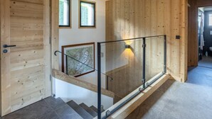 Un interior de madera con una escalera de cristal, una puerta y dos ventanas.