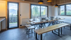 Comedor con una mesa larga dispuesta para cuatro personas, bancos e iluminación colgante.