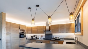 Una cocina moderna con armarios de madera, una isla central e iluminación colgante.