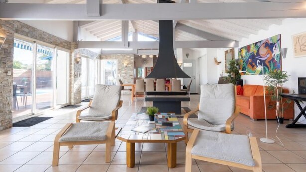 Een ruime woonkamer met een grote tafel, comfortabele zitplaatsen, een open haard en uitzicht op de omgeving.