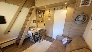 A cozy living room with a wooden staircase, a dining area, and a couch.