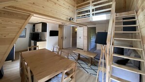 A wooden interior with a loft bedroom, a dining area, and a kitchen.