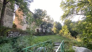 A stone wall, a wooden staircase, and a grassy area with trees.