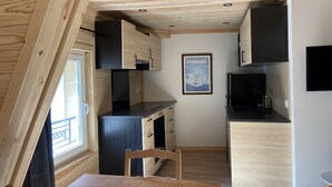 A compact kitchen with wooden cabinets, a black countertop, and a framed poster on the wall.