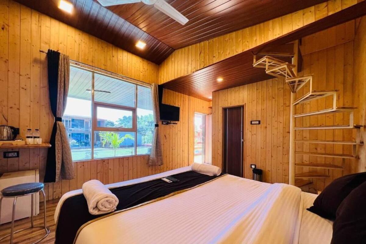 A wooden-paneled room with a bed, a desk, and a window.
