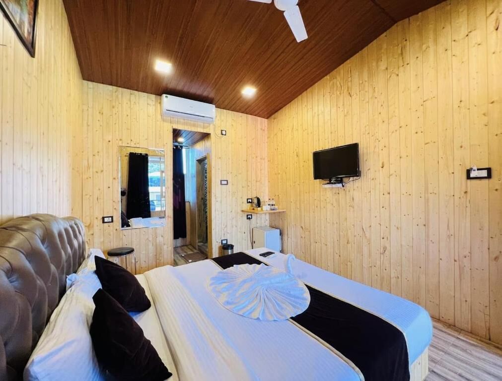Ein Zimmer mit Holzwänden, einem Bett, einer Couch, einem Fernseher und einer Klimaanlage.