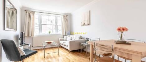 A modern living room with a sofa, a dining table, and a TV.