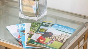 A glass table with brochures and a clear vase with green plants. - 2 Bed Apt| Parking| Central Windsor By Tempstay (Windsor)